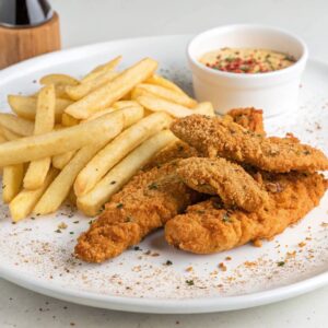 Plate of crispy chicken tenders and fries with dipping sauces, perfect for a quick weeknight meal.