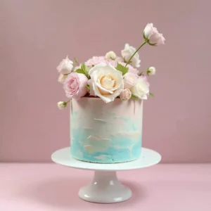 A beautifully decorated gender reveal cake with pastel pink and blue frosting, sliced to show its colored filling. 