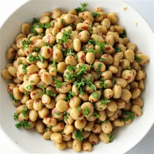 Close-up of a spoon serving a vibrant, protein-packed dense bean salad with fresh vegetables and a lemon vinaigrette.