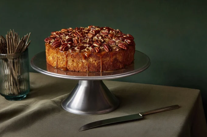 Whole pecan cake with brown sugar glaze on a wooden stand