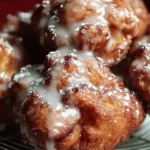 Freshly made cinnamon apple fritters dusted with powdered sugar.