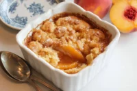 Easy Bisquick peach cobbler recipe baked golden brown in a rustic dish