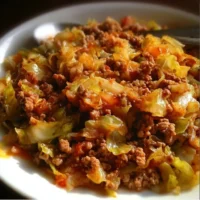 Plate of ground beef and chopped cabbage stir-fry with spices and herbs.