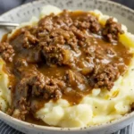Ground beef and gravy served over creamy mashed potatoes in a bowl