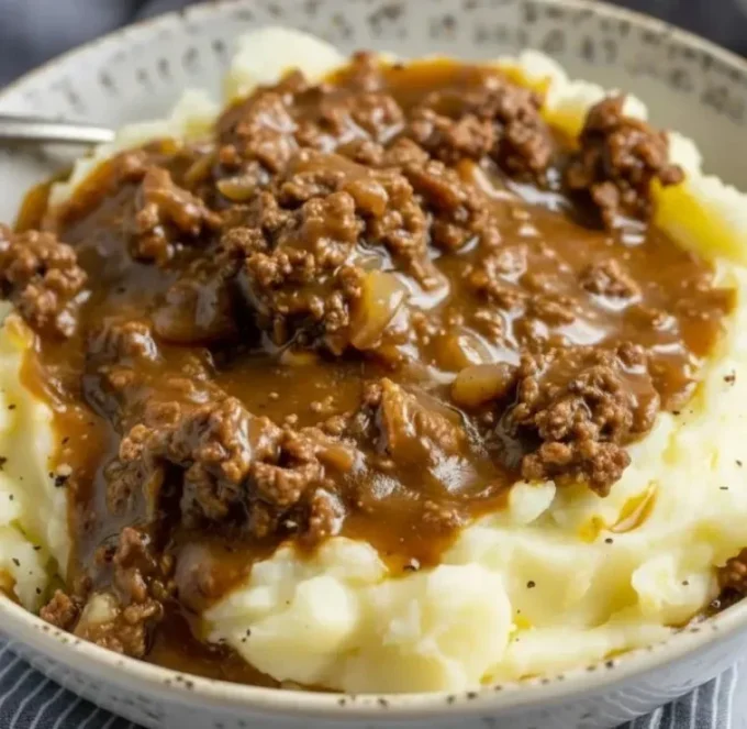 Ground beef and gravy served over creamy mashed potatoes in a bowl