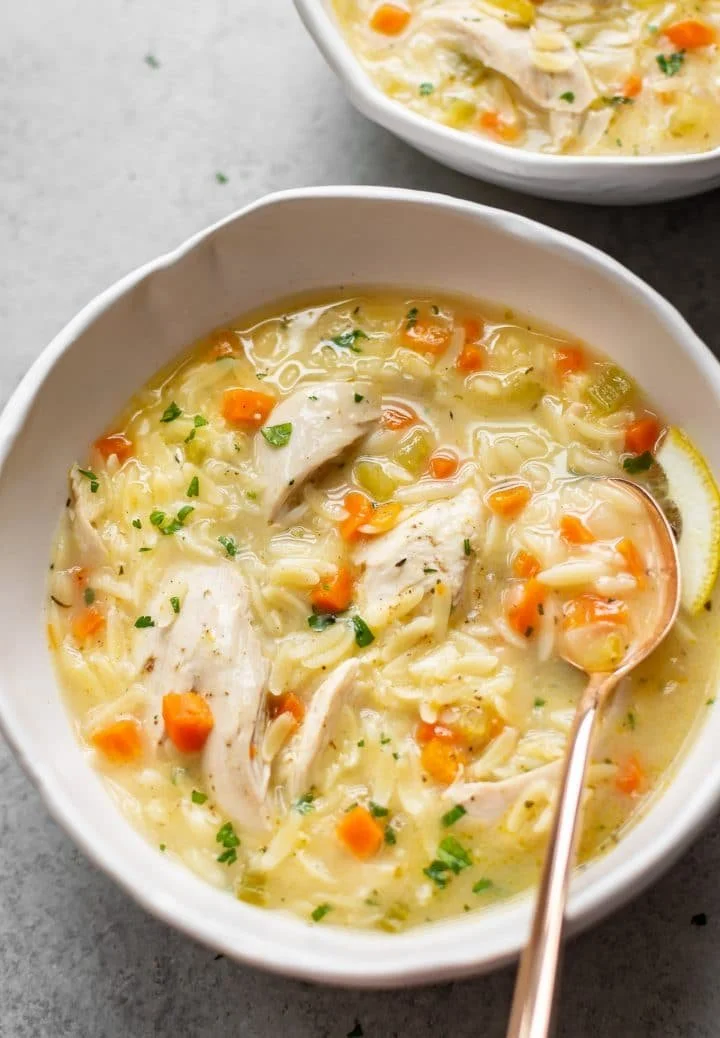 Bowl of delicious Lemon Chicken Orzo Soup garnished with herbs