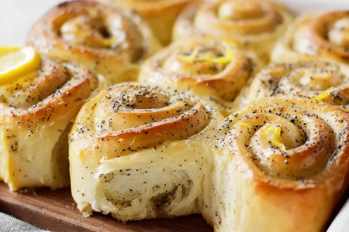 Freshly baked Lemon Poppy Seed Rolls on a wooden table.