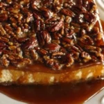 Delicious pecan pie cheesecake topped with caramel and pecans