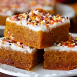 Delicious homemade pumpkin bars with cream cheese frosting on a rustic wooden table