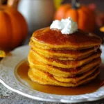 Delicious stack of pumpkin pancakes topped with syrup and cinnamon