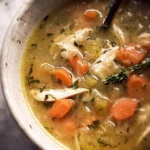 A bowl of Slow Cooker Hearty Chicken Soup with vegetables and herbs.