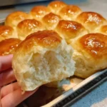 Freshly baked soft and buttery homemade rolls on a wooden table