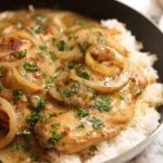 Southern smothered chicken recipe served in a skillet over rice with onion gravy