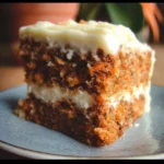 Slice of the best carrot cake ever with cream cheese frosting on a plate