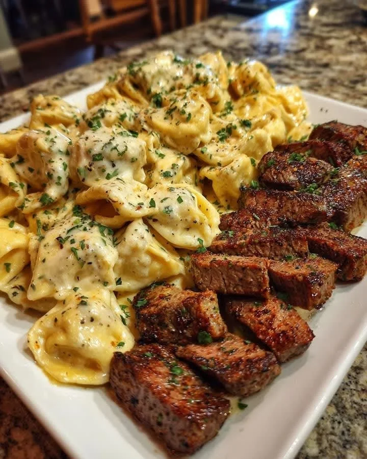 Delicious Cajun Garlic Butter Steak with Cheesy Alfredo Tortellini served on a plate.