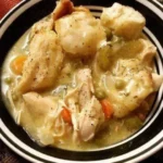 A comforting bowl of Crock Pot chicken and dumplings served with biscuits.