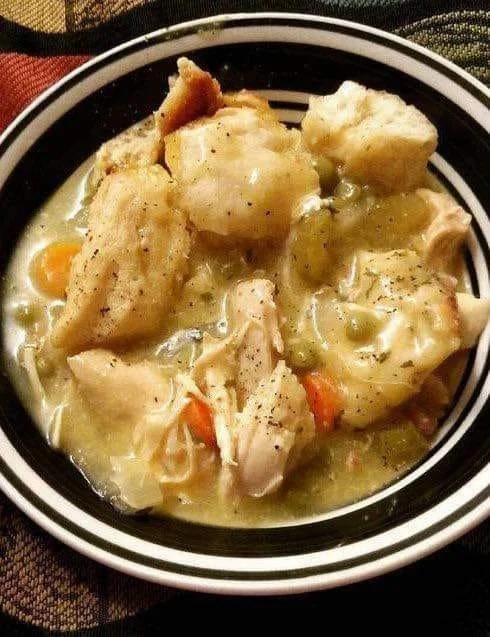 A comforting bowl of Crock Pot chicken and dumplings served with biscuits.