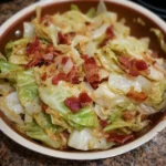 Delicious fried cabbage with bacon, onion, and garlic on a plate