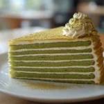 Slice of Matcha Mille Crepe Cake showcasing layers of crepes and matcha cream.