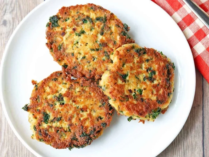 Delicious pan-fried salmon cakes served on a plate with fresh herbs.