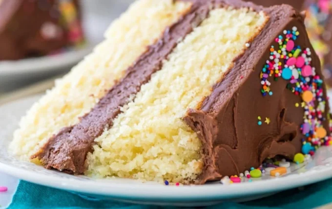 Delicious homemade vanilla cake topped with creamy frosting and fresh berries.