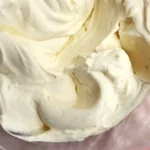 Vanilla whipped ganache frosting in a bowl, ready to decorate desserts.