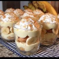 Individual banana pudding cups topped with whipped cream and bananas