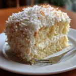 Delicious creamy coconut cake topped with shredded coconut and frosting
