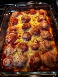Baked meatball pasta with melted cheese and herbs on top