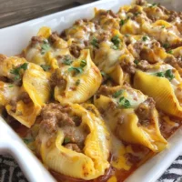Cheesy taco stuffed pasta shells topped with melted cheese and fresh herbs