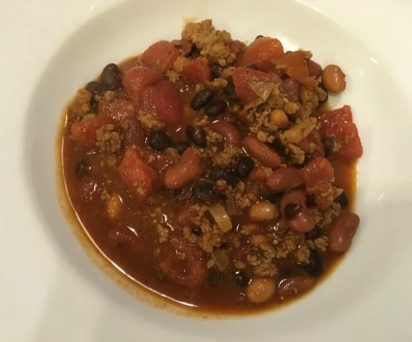 Bowl of Jamie's Award-Winning Chili garnished with fresh herbs and ingredients.