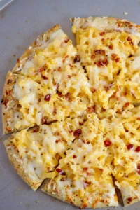 Slice of Mac and Cheese Pizza topped with macaroni and melted cheese