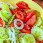 Delicious marinated cucumbers with onions and tomatoes in a bowl