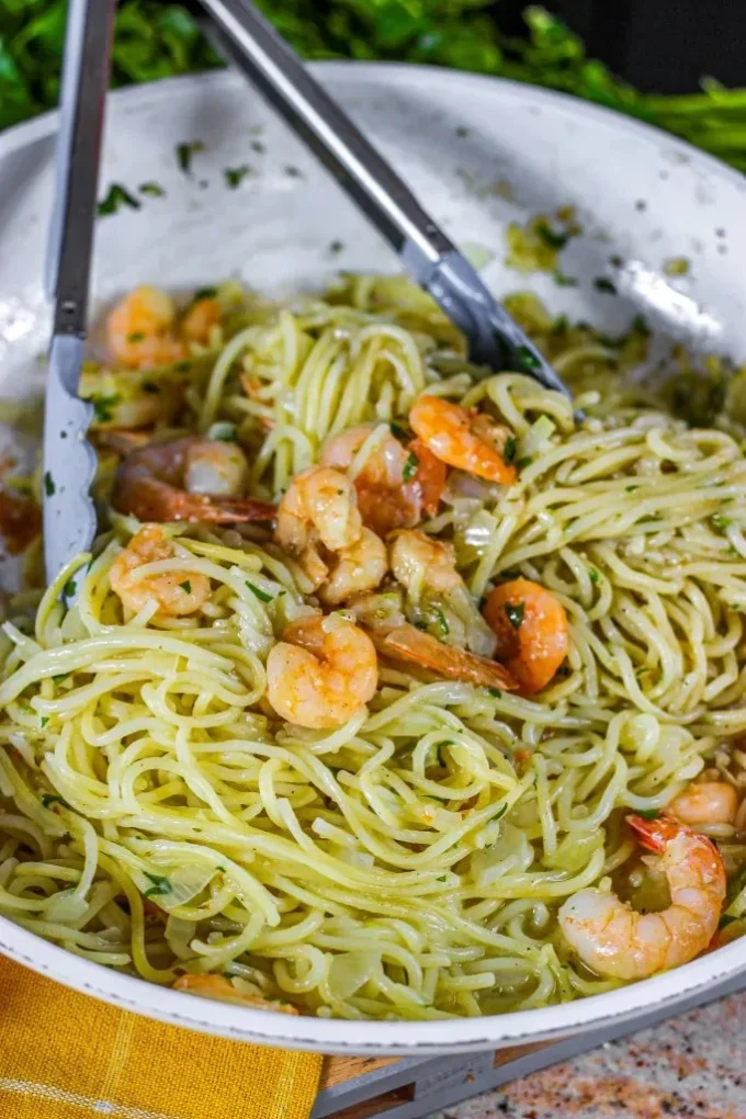 Plate of shrimp scampi with spaghetti garnished with parsley and lemon.