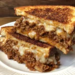 Melted cheese and sloppy joe filling in a grilled cheese sandwich