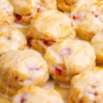 Freshly baked strawberry biscuits on a wooden table.