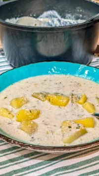 Bowl of warm garlic potato soup with fresh herbs on top