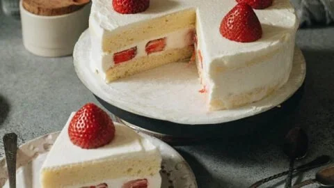 Slice of Japanese Strawberry Cake topped with fresh strawberries and whipped cream