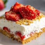 Delicious no-bake strawberry dessert topped with fresh strawberries and whipped cream.