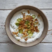 Silky dill pickle dip served in a bowl with fresh herbs and crackers.