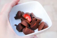 Chocolate-dipped frozen strawberry bites on a plate