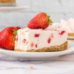 Slice of strawberry no-bake cheesecake topped with fresh strawberries