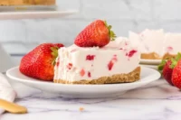 Slice of strawberry no-bake cheesecake topped with fresh strawberries