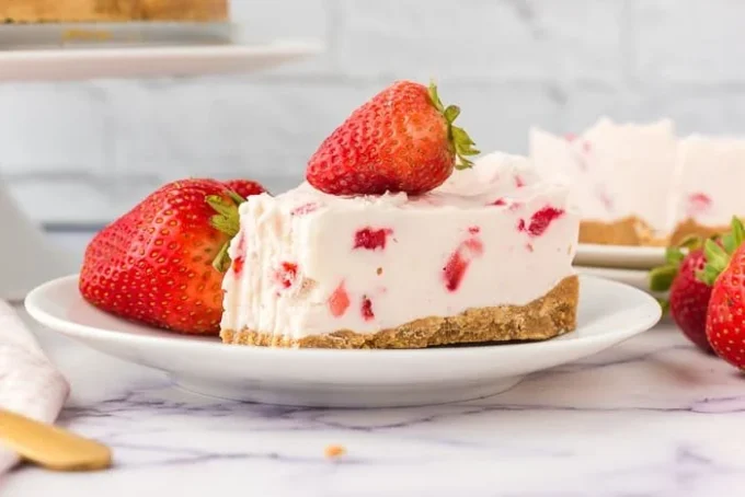 Slice of strawberry no-bake cheesecake topped with fresh strawberries