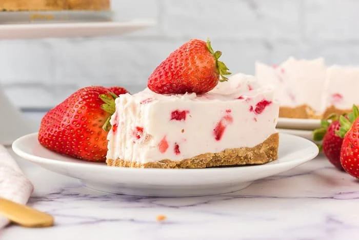 Slice of strawberry no-bake cheesecake topped with fresh strawberries