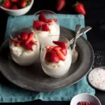 Strawberry-topped white chocolate mousse served in elegant bowls.